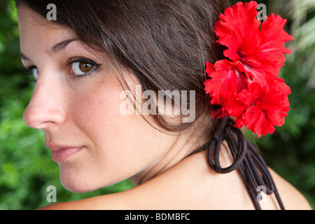 Porträt einer jungen Frau mit einer roten Hibiskus Blume im Haar Stockfoto