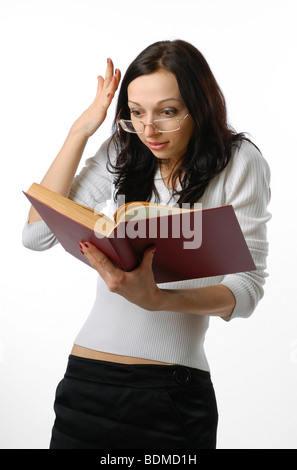 Schockiert Mädchen liest das große Buch und expressiv erstaunt. Junge Brünette trägt schwarzen Rock und weißer Bluse. Stockfoto