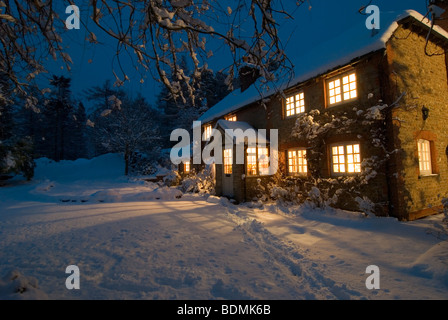 Weihnachtsszene Berghütte als Nacht fängt an, umgeben von Schnee fallen Stockfoto