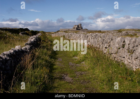Steinmauern Feldweg mit Dun Arann Signalsäule hinter Inis Mor (Inismore) Insel, Aran-Inseln, County Galway, Irland. Stockfoto
