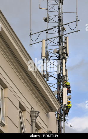 Zwei Männer arbeiten empor auf einem Fernmeldeturm hinter dem Bridewell Garda (Polizei)-Bahnhof in Dublin Irland Stockfoto