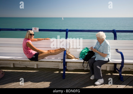 Zwei Menschen sitzen auf einer Bank auf dem Pier in Eastbourne, England. Stockfoto