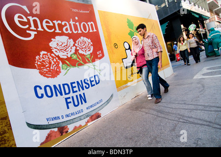 BEIRUT: Ein junges Paar geht vorbei an Plakatwänden auf Hamra Street, Beirut. Stockfoto