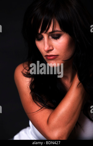 Junge Frau mit dunklem Haar, nachdenklich Stockfoto