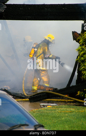 Haus Dachschindel Auto Rauch Flamme Brandgefahr, dass Risiko Maske Helm Sauerstoff Tank Schlauch Spray löschte Feuerwehrmann kämpfen zu löschen Stockfoto