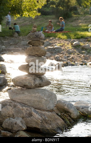 Stein-Skulptur und Menschen beim Grillen am Fluss Stockfoto