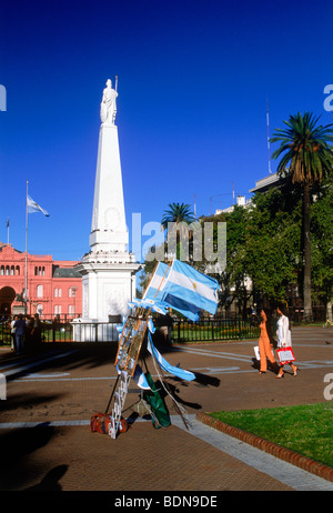 Menschen und Statue am Plaza de Mayo in Buenos Aires mit argentinischen Souvenir Fahnen Stockfoto