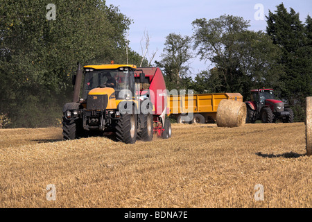 Traktor und Stroh Ballenpresse arbeitet auf einem Gebiet Stockfoto