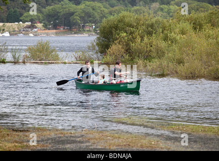 Zwei Männer und ein Junge in einem grünen Kanu an einem Fluss zu Loch Lomond, Schottland. Stockfoto