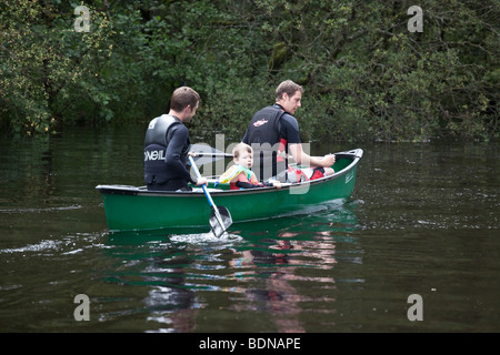 Zwei Männer und ein Junge in einem grünen Kanu an einem Fluss zu Loch Lomond, Schottland. Stockfoto