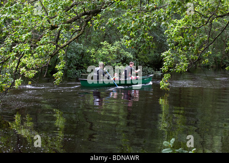 Zwei Männer und ein Junge in einem grünen Kanu an einem Fluss zu Loch Lomond, Schottland. Stockfoto