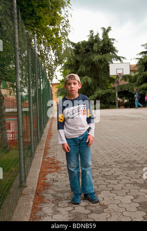 Ricky nach der Schule an einem Frühlingstag, Basketball hoop im Hintergrund, ist es den Schulhof in Armeno, VB, Italien Stockfoto