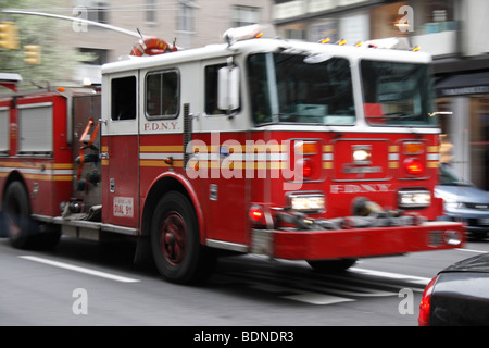 Ein schnelllebiger (und VERSCHWOMMEN) Fire Department New York Feuerwehrauto vorbei an einer belebten Straße, New York, Vereinigte Staaten von Amerika siehe Beschreibung Stockfoto