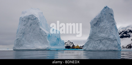 Riesige Blaue Eisberge Bellingshausen Meer aufragende westlichen Antarktis in der Nähe der Insel unheimliche Moody bedecktem Himmel, große Kreuzfahrtschiff fügt Perspektive Skala Stockfoto