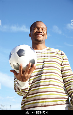 Mann lächelnd hält Fußball Ball im Freien, Cape Town, Western Cape Province, Südafrika Stockfoto
