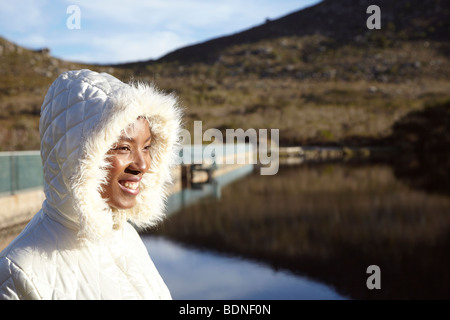 Frau trägt warme Kapuzenjacke lächelnd im Freien, Cape Town, Western Cape Province, Südafrika Stockfoto