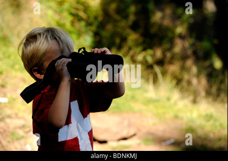 Kleiner Junge Blick durch das Fernglas im freien Stockfoto