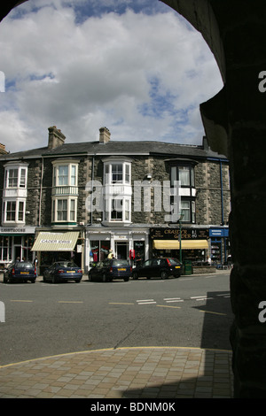 Die Stadt von Wales, Wales. Ortszentrum Geschäfte durch die Bögen des Neuadd Idris, die ehemalige Markthalle betrachtet. Stockfoto