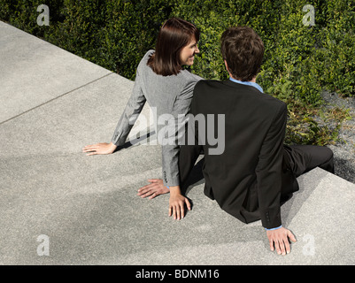 Hinten Sie Business-Mann und Frau sitzen an Wand im Freien, Ansicht von Stockfoto