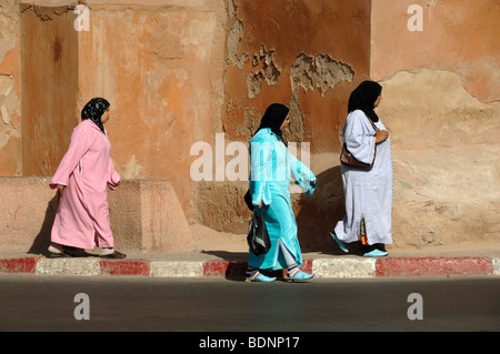 Marokkanische Frauen tragen Kopfbedeckungen & bunte bunten Kostümen gehen vorbei an der Stadtmauer von Marrakesch, Marokko Stockfoto