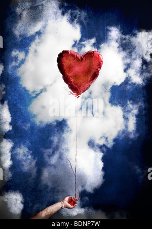 Eine Mädchen hält ein roter Ballon geformt mochte ein Herz gegen den blauen Himmel. Stockfoto