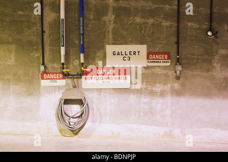 Warnschilder mit Rohr-Fittings an einer Wand Stockfoto