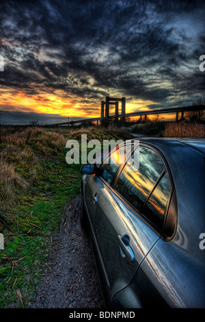 Abendsonne über dem Fluß Swale spiegelt sich in der Seite ein glänzendes Auto mit den neuen und alten Swale Brücken am Horizont Stockfoto