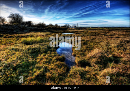 Bewölkten blauen Aky spiegelt sich in einer Pfütze Marschland entlang Faversham Creek mit den alten Oysterhouse und Bootswerft im Hintergrund, Stockfoto