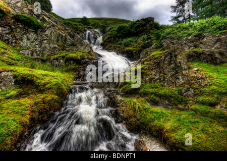 Die majestätische Kraft einer Langzeitbelichtung Aufnahme eines Wasserfalls im Lake District mit Wasser über die Felsen stürzt Stockfoto