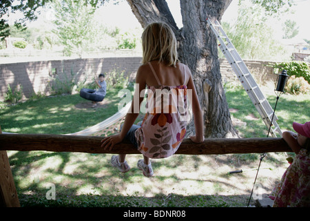 Rückansicht des Mädchen sitzen auf Balken im Hinterhof Stockfoto