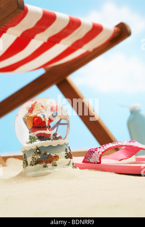 Souvenir-Santa-Schneekugel unter Liegestuhl am Strand, Nahaufnahme Stockfoto