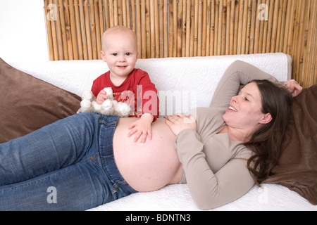 Schwangere Frau mit einem Kleinkind auf dem Sofa spielen Stockfoto