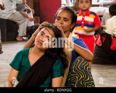 Eine Frau, die den Kopf eines Mädchens in Mumbai Central Station zu überprüfen. Mumbai. Indien. Stockfoto