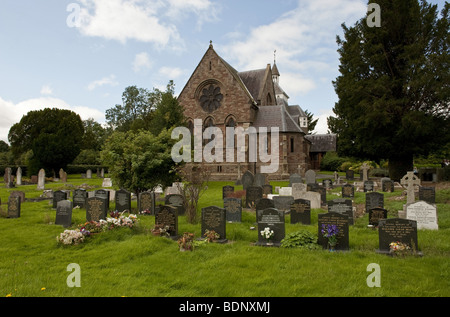 Giebelseite des ländlichen Steinmauern Dorfkirche gesehen über die Grabsteine auf dem Friedhof an einem blauen fuhr Sommertag Stockfoto