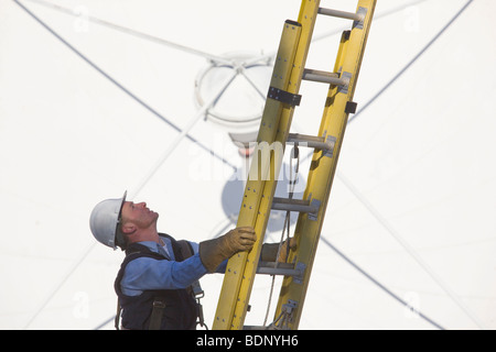 Kabel-Lineman Aufstieg vor einer Satellitenschüssel Stockfoto