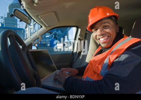 Ingenieur auf einem Laptop in einem Auto Stockfoto