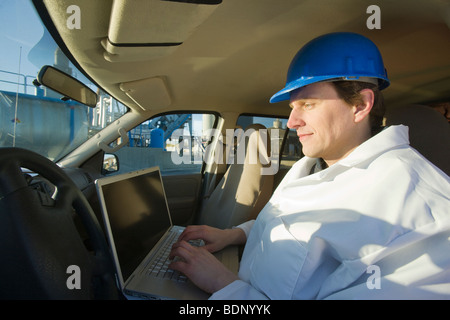 Ingenieur auf einem Laptop in einem Auto Stockfoto