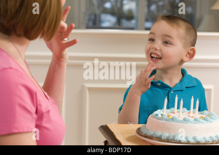 Frau, die das Wort "Geburtstag" in amerikanischer Gebärdensprache während der Kommunikation mit ihrem Sohn Unterzeichnung Stockfoto