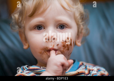 Ein-jähriger Junge mit schokoladenbedeckten Fingern Stockfoto