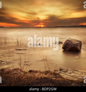 Untergehende Sonne über einen gefrorenen See Stockfoto