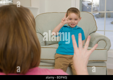 Frau, die Unterzeichnung der Zahl "4" in amerikanischer Gebärdensprache während der Kommunikation mit ihrem Sohn Stockfoto