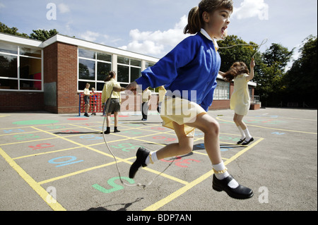 Schulmädchen überspringen in einer Grundschule Spielplatz im Vereinigten Königreich. Stockfoto
