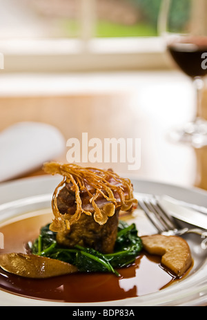 Knusprige Ente auf Blattspinat mit Rotwein in einem Restaurant serviert. Stockfoto