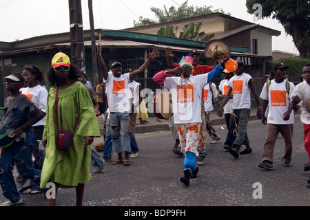 Karnevalsumzug Bonapriso Bezirk Douala Kamerun Westafrika Gruppe tragen Orange Handy-T-shirts Stockfoto