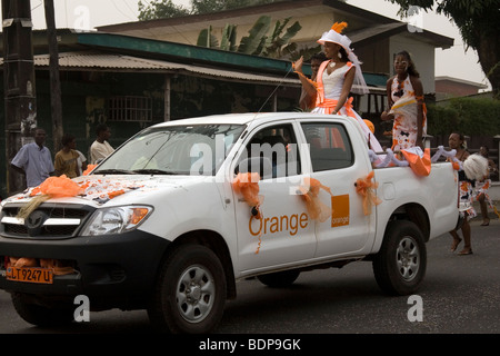 Karnevalsumzug Bonapriso Bezirk Douala Kamerun Westafrika Orange Mobiltelefon Werbe Schwimmer Stockfoto