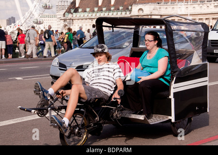 Jungen Fahrrad Rikscha über Westminster Bridge mit Beifahrerin, London, UK Stockfoto