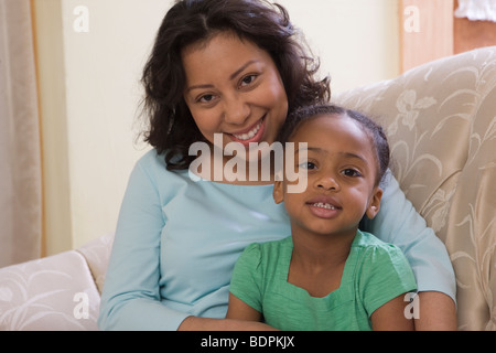 Hispanic Frau mit ihrer Tochter auf einer Couch sitzend Stockfoto