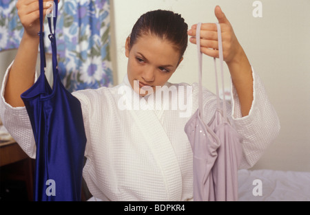 Frau versucht, die Wahl zwischen 2 Kleider in verschiedenen Farben Stockfoto