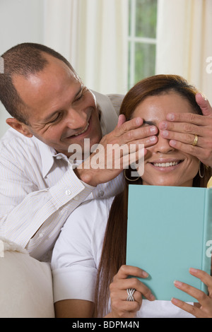 Hispanische Manndeckung Augen einer Frau von hinten Stockfoto