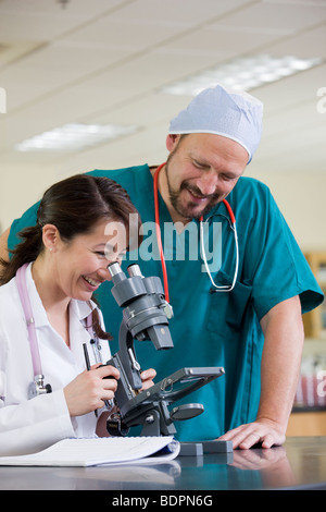 Weibliche Laborantin Analyse einer Probe durch ein Mikroskop Stockfoto